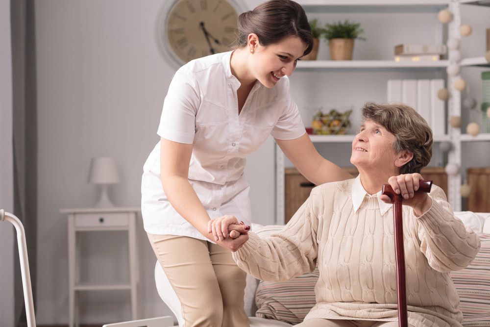 A Nurse is Helping an Elderly Woman With a Cane — Active Lifestyle Supports In Tullimbar, NSW