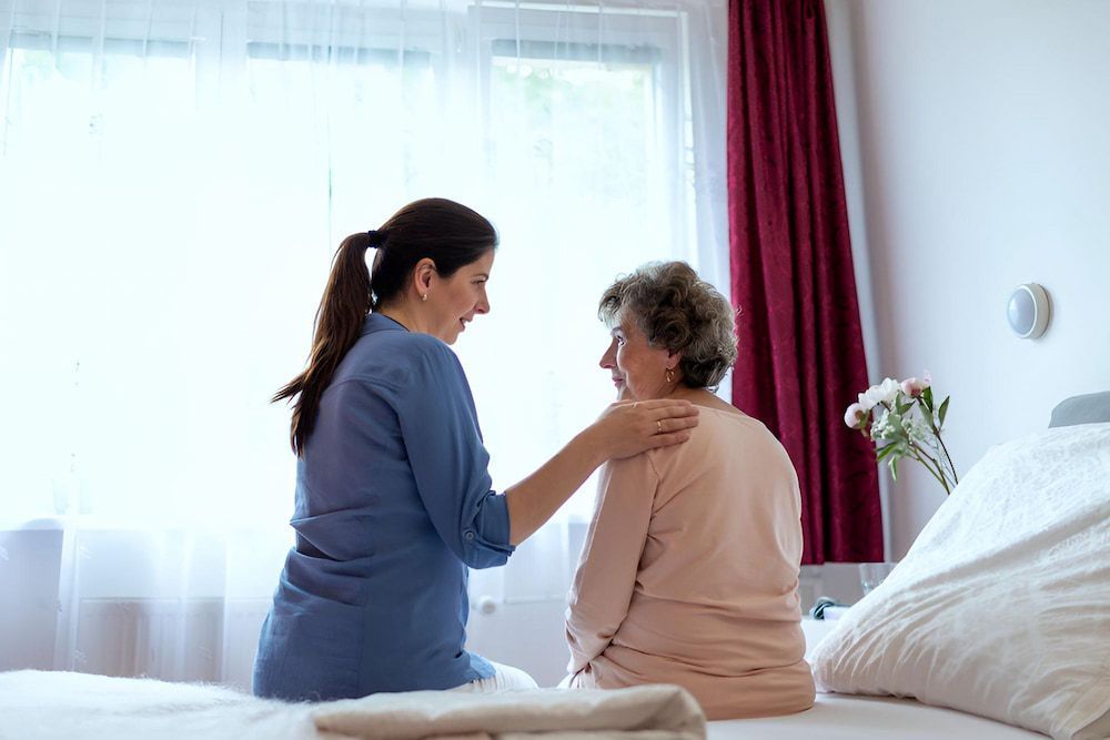 A Nurse is Talking to an Elderly Woman Sitting on a Bed — Active Lifestyle Supports In Tullimbar, NSW