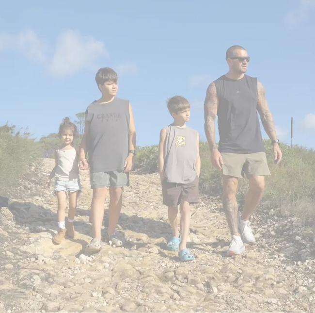 Family hiking on a sunny day. Four people walking on a dirt path with blue sky.