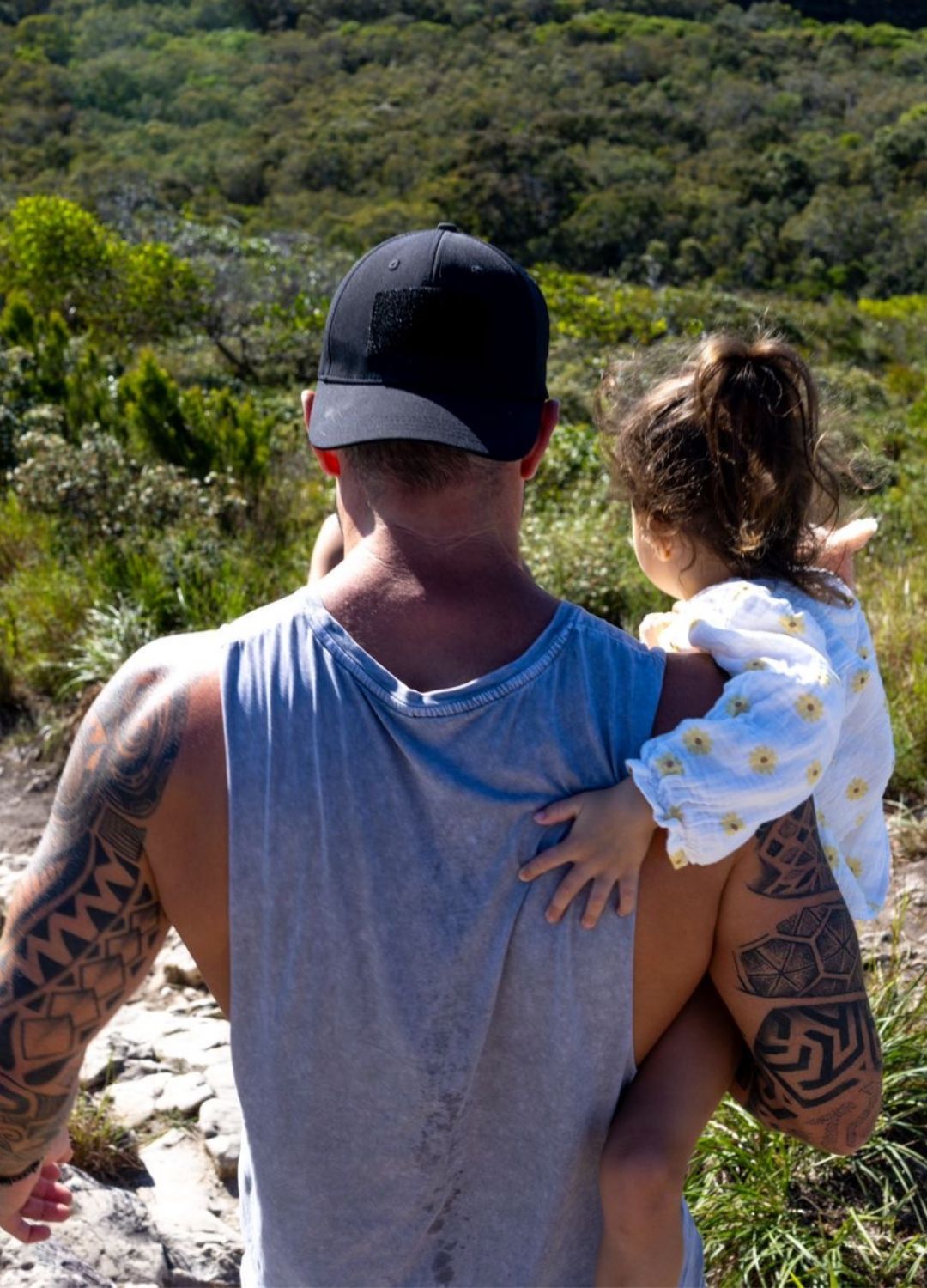 Man carrying a child on a hillside.
