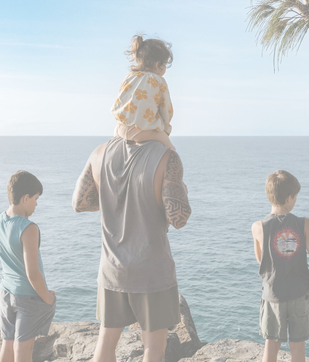 Family hiking on a sunny day. Four people walking on a dirt path with blue sky.