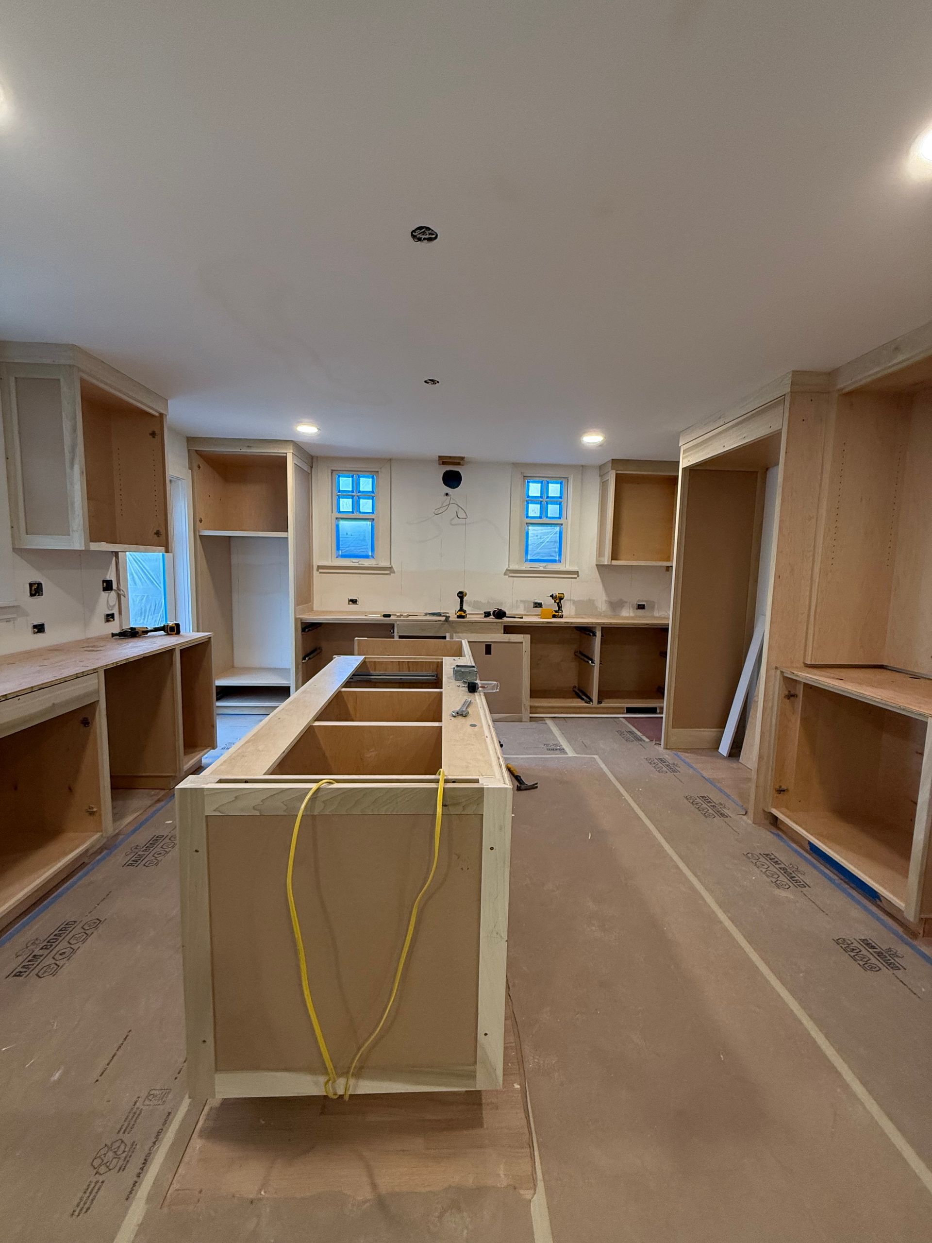 A room under construction featuring an orange waterproof floor membrane, unfinished walls, and a shower curb installation.