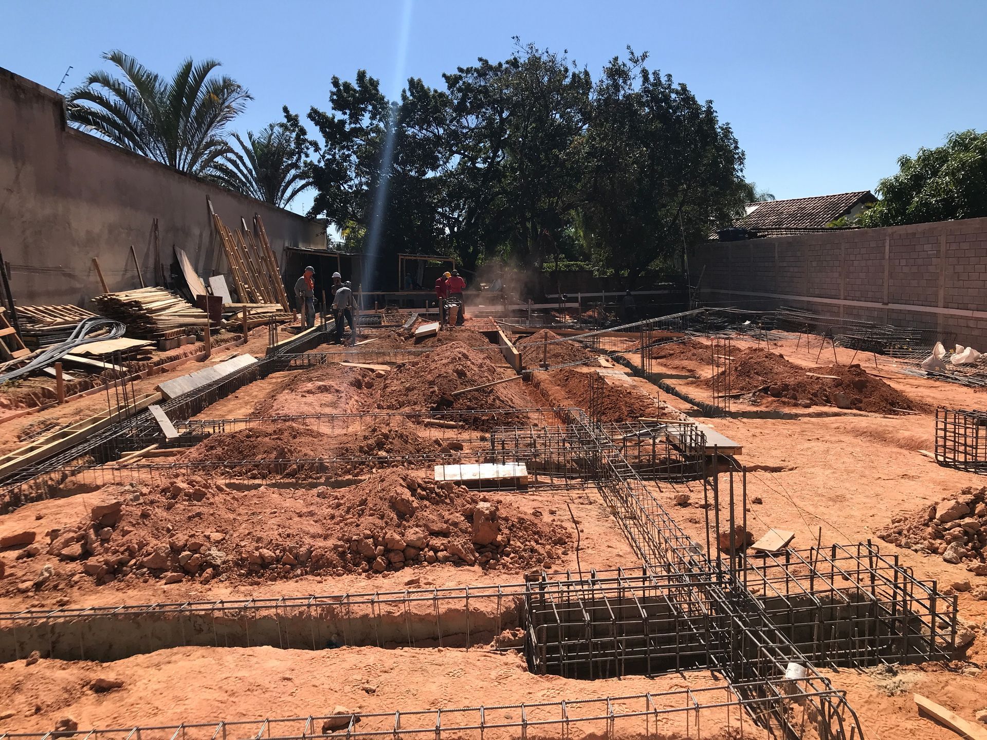 Um canteiro de obras com uma cerca e árvores ao fundo