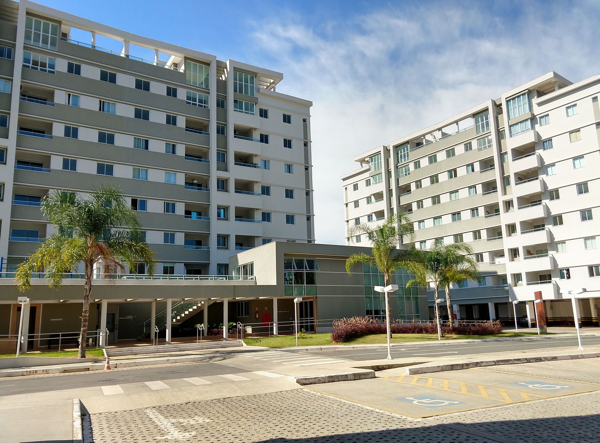 Um grande prédio de apartamentos com palmeiras na frente