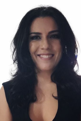 Woman with black hair smiles, wearing a black sleeveless top, against a white background.