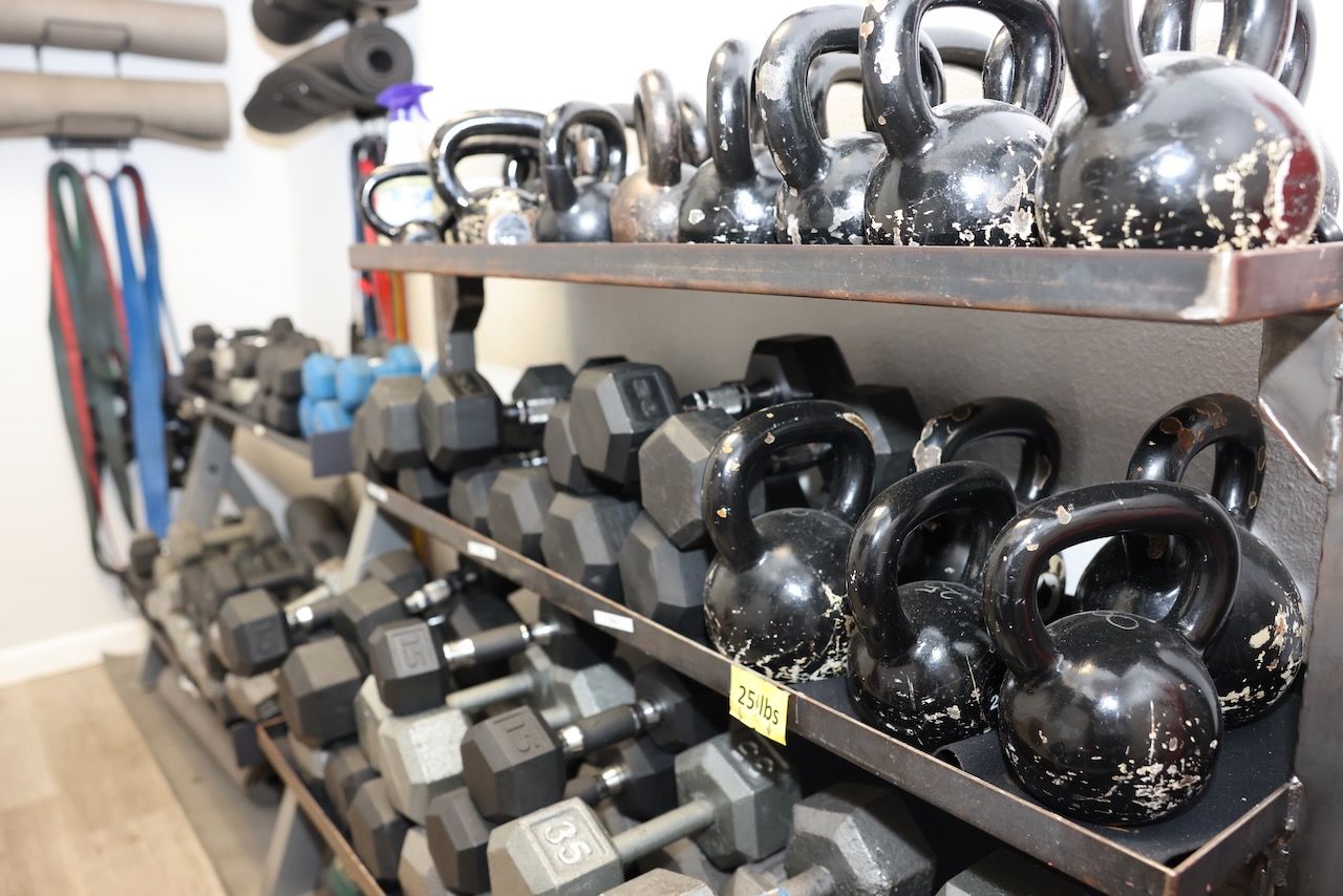A shelf filled with a variety of dumbbells and kettlebells.
