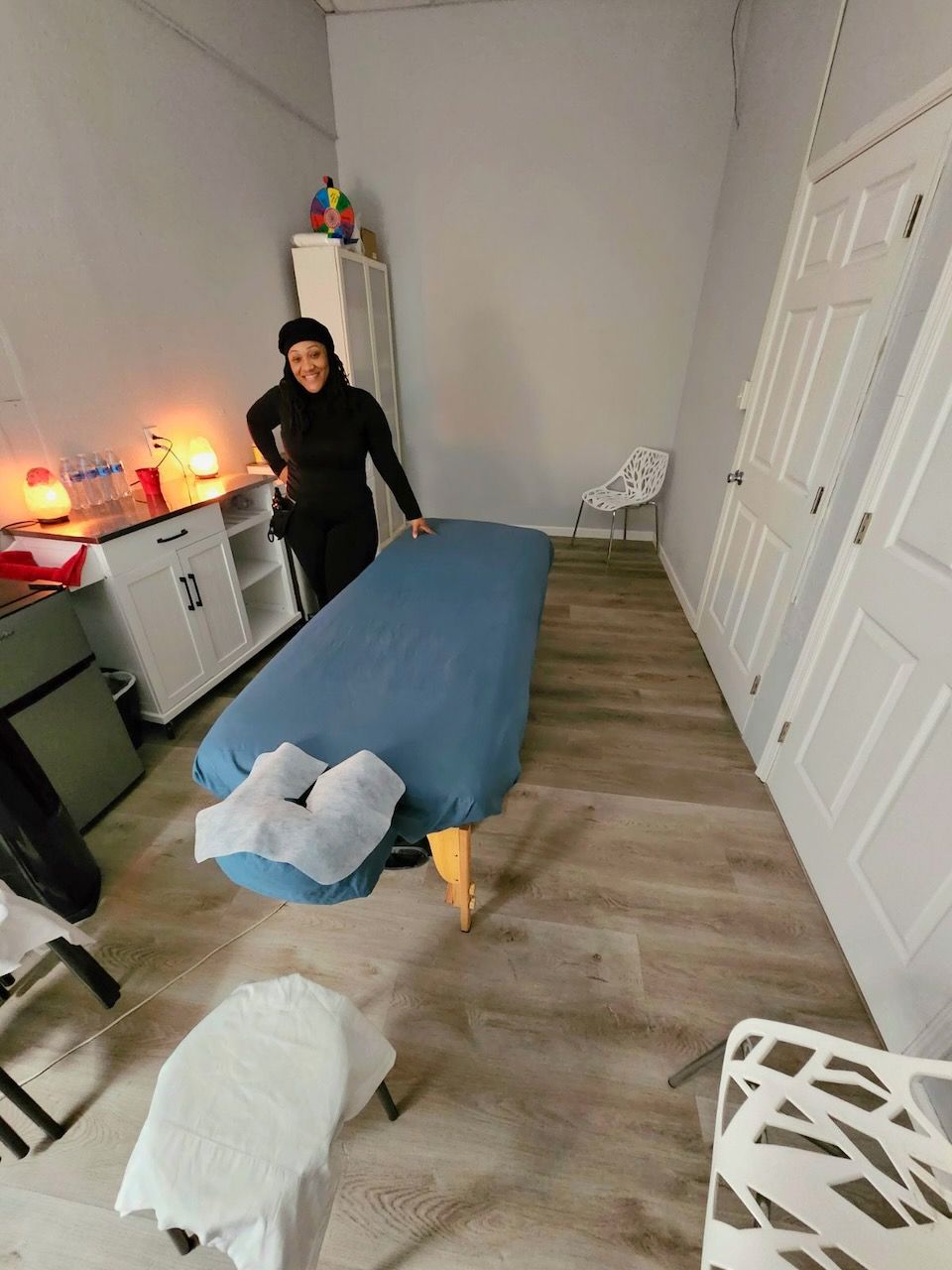 A woman is standing next to a massage table in a room.