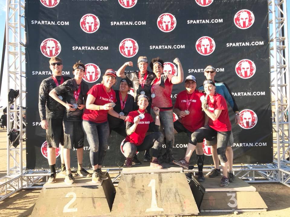 A group of people are posing for a picture in front of a spartan wall.