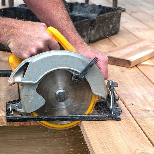 A man is using a circular saw to cut a piece of wood