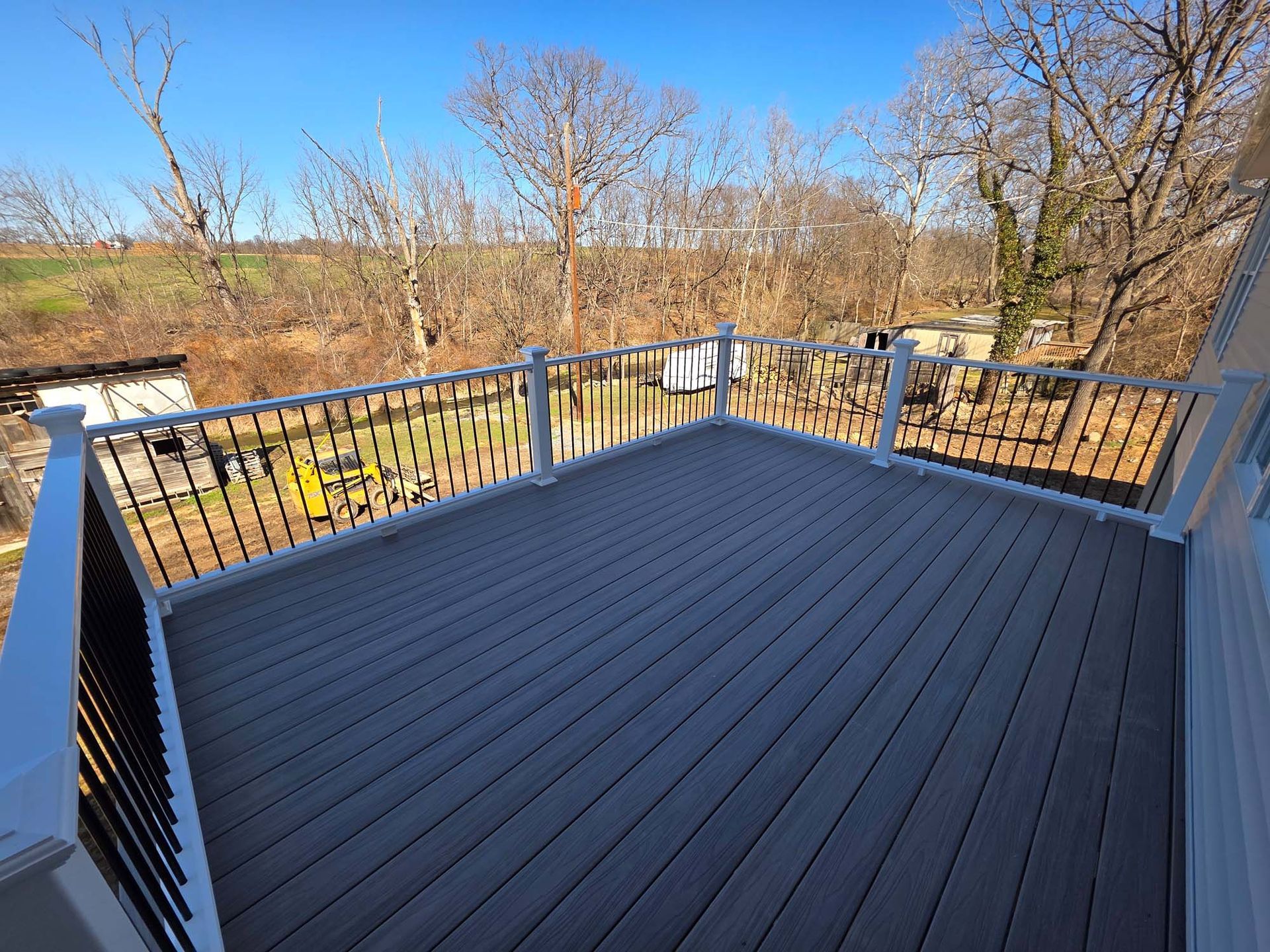 An empty deck with a railing and trees in the background