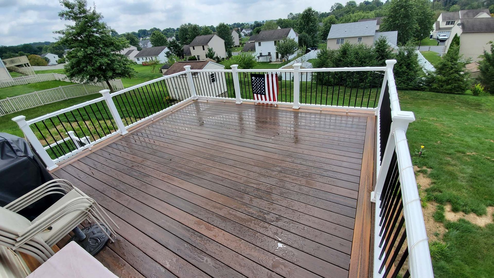 A wooden deck with stairs leading up to it next to a white house.