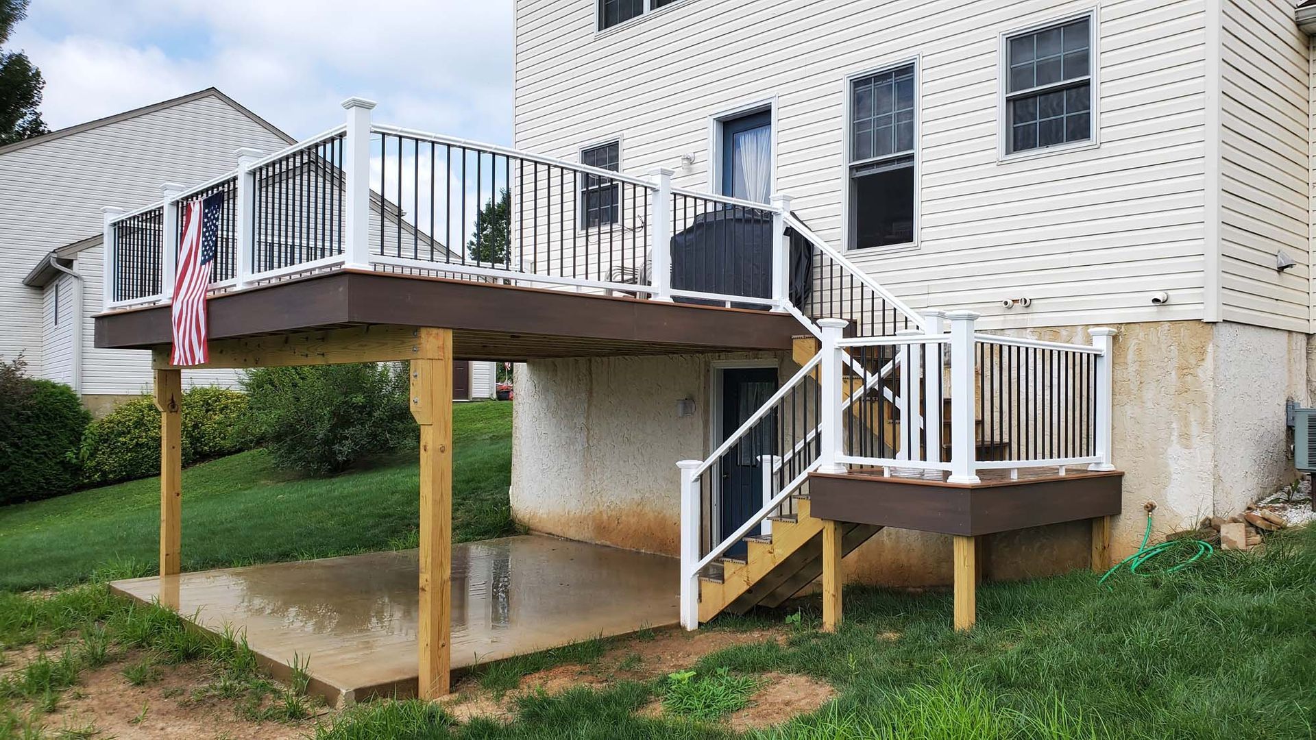 A deck with stairs leading up to it is in the backyard of a house.