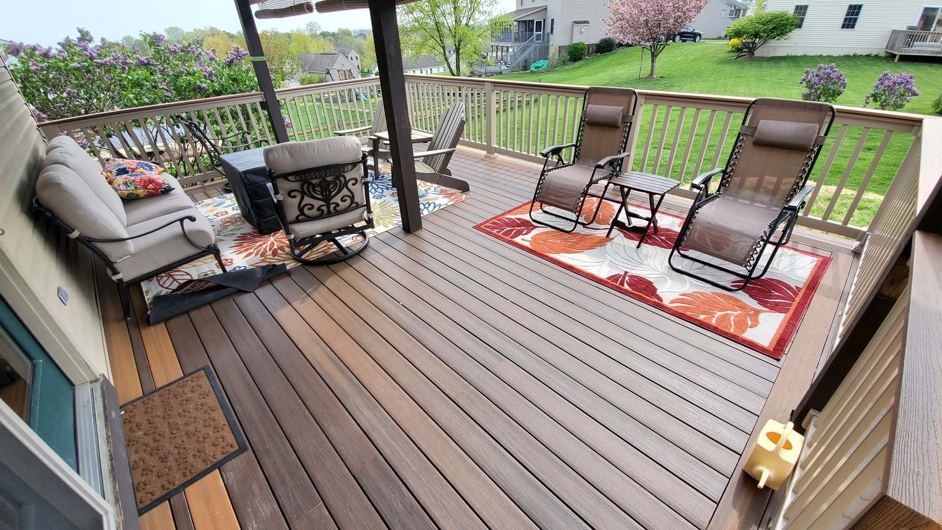 A wooden deck with a rug and chairs on it.