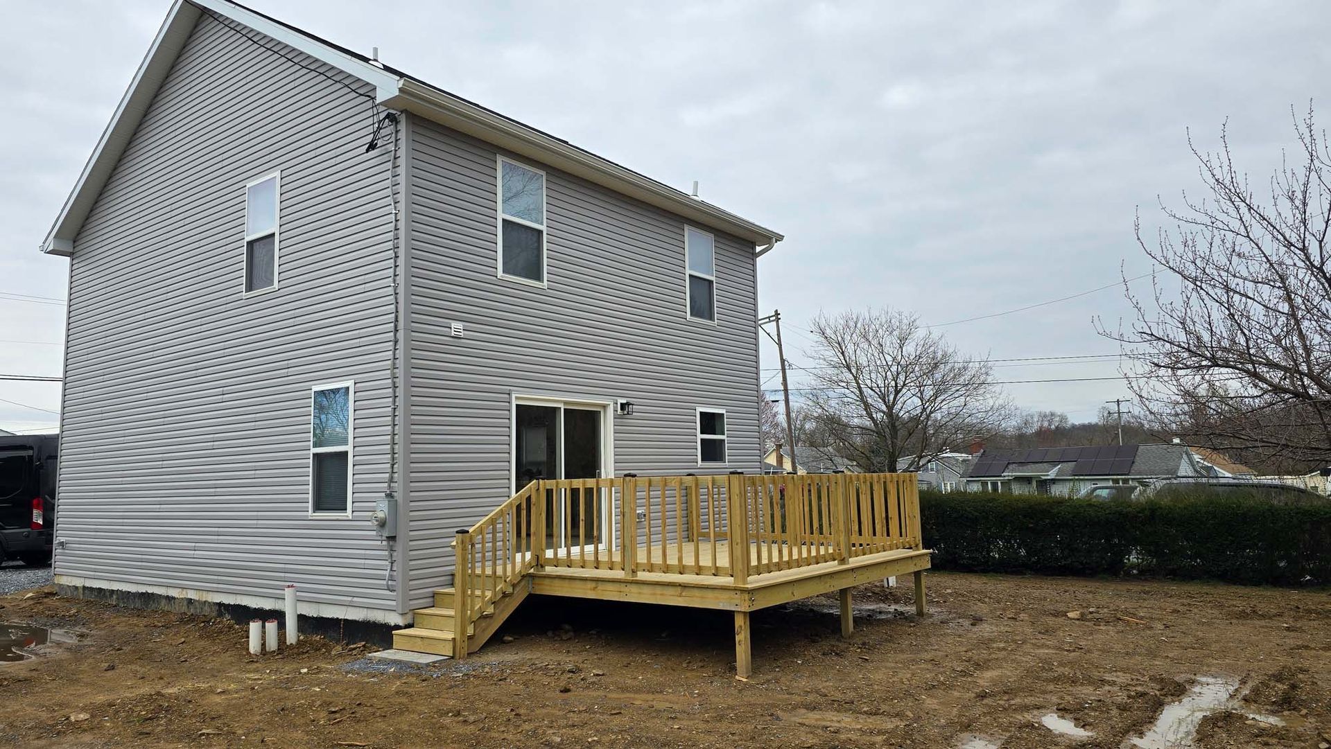 The back of a house with a wooden deck and stairs.