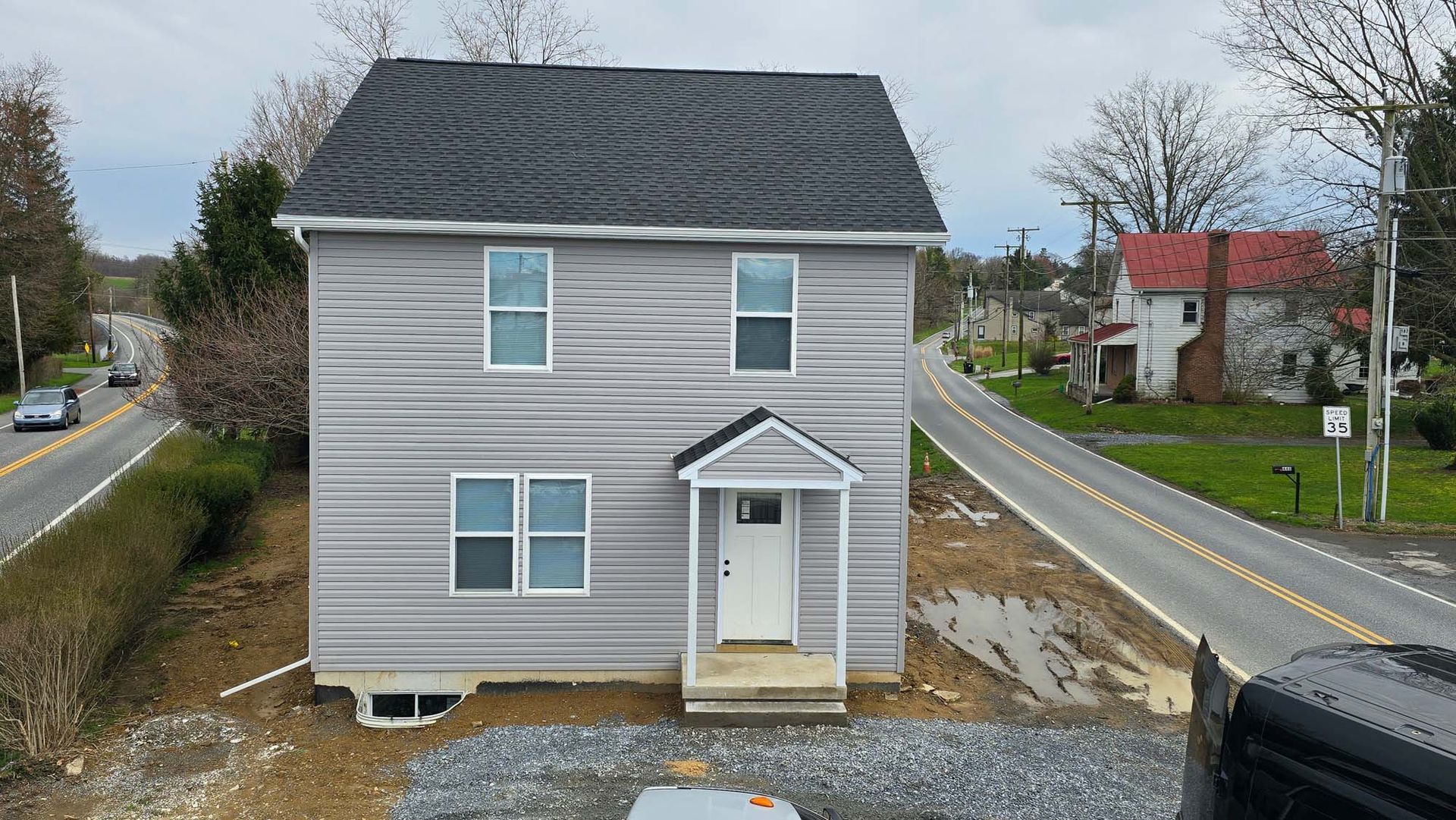 A small house is sitting on the side of a road next to a road.