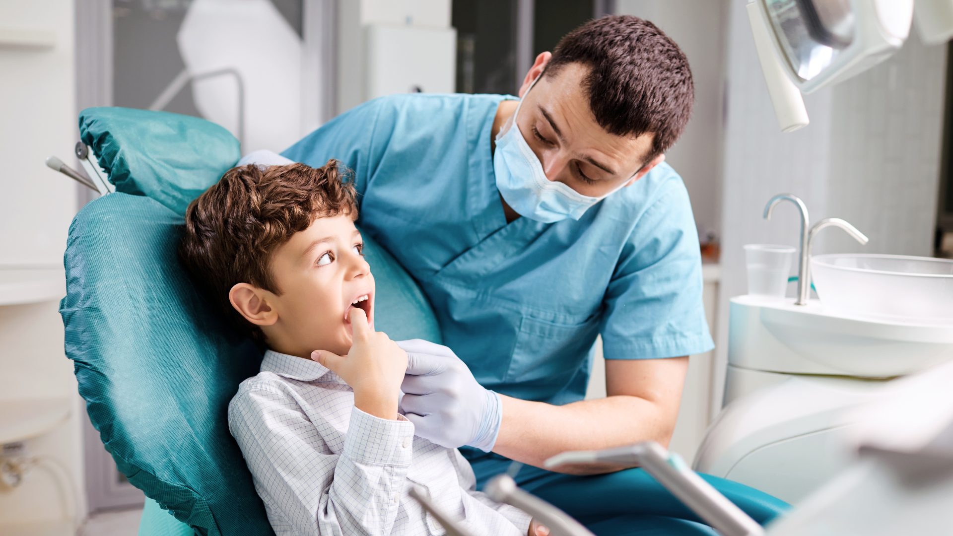 a young boy is sitting in a dental chair talking to a dentist .