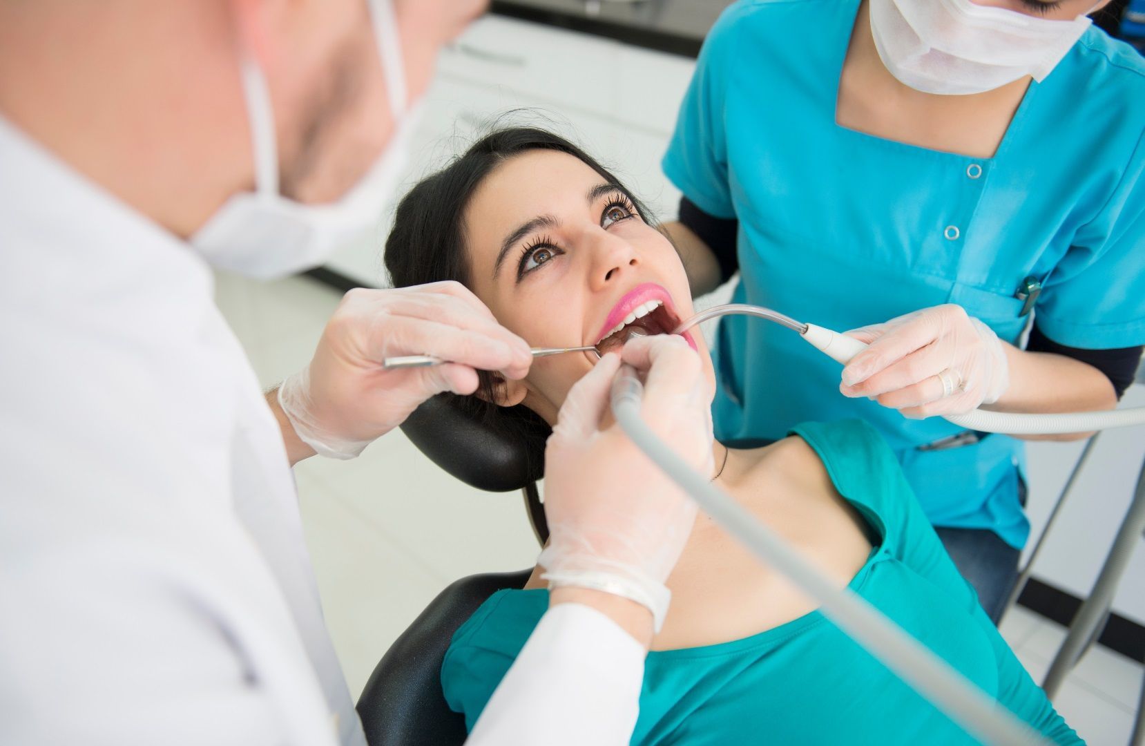 A woman is smiling while sitting in a dental chair.