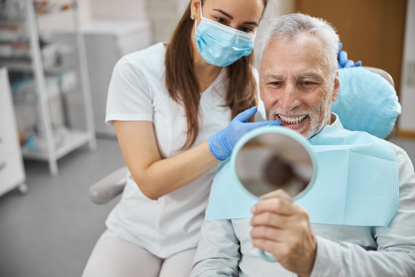 A woman is smiling while sitting in a dental chair.