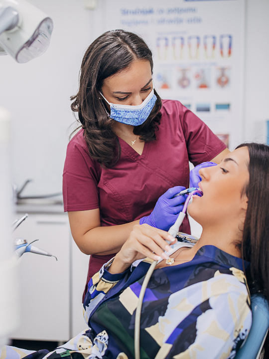 A woman is smiling while sitting in a dental chair.