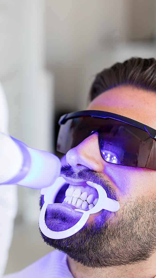 A woman is smiling while sitting in a dental chair.