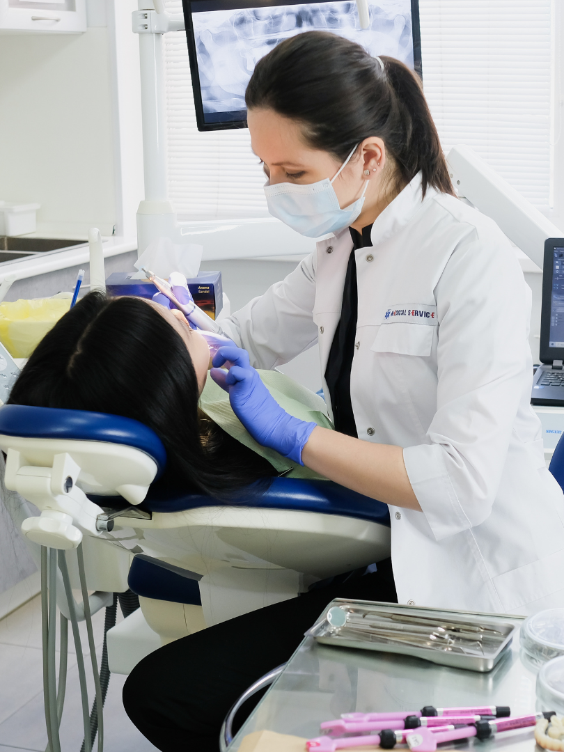 A woman is smiling while sitting in a dental chair.