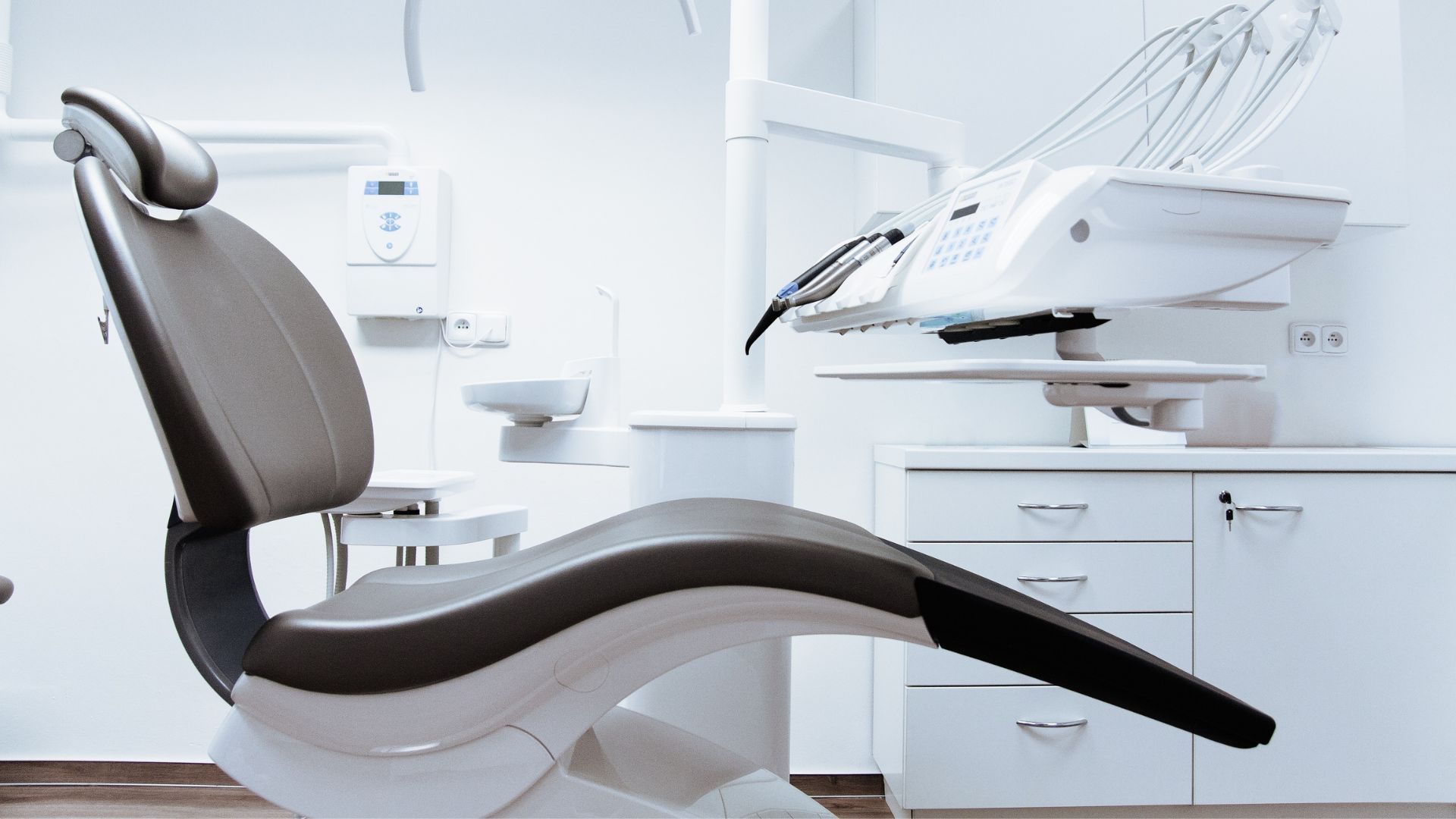 Modern dental exam room with a reclining chair and overhead dental equipment