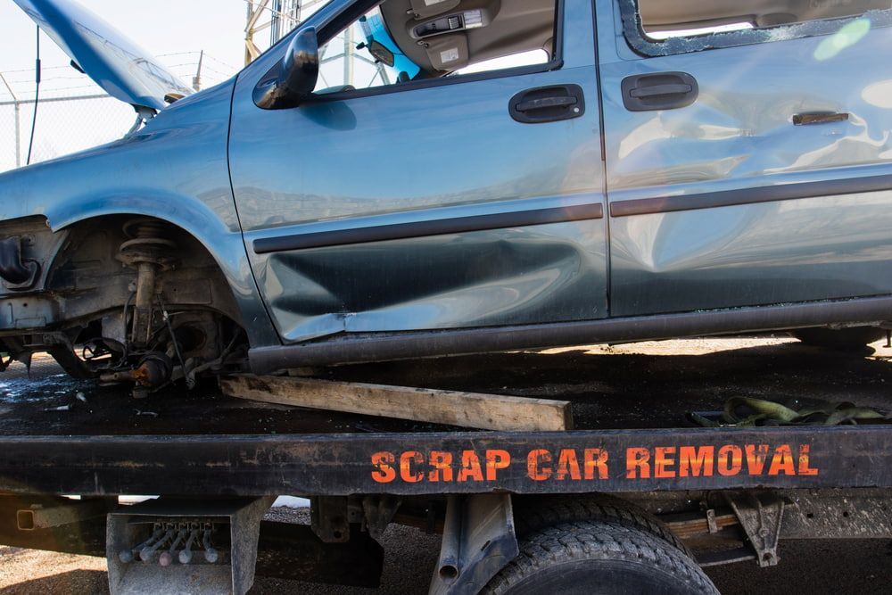 Damaged Teal Minivan Loaded on a Tow Truck, Labelled — Central Scrap Metal in Willawong, QLD