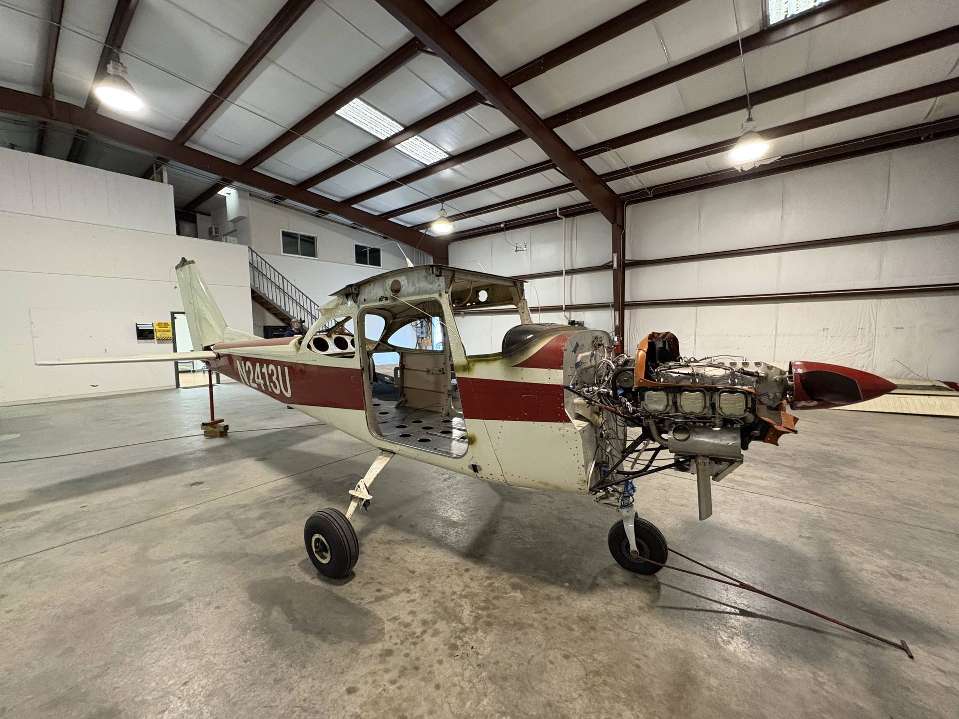 A small plane is parked in a hangar with the engine exposed