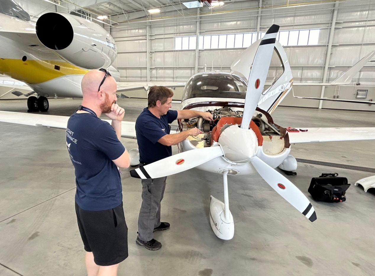 Two men are working on an airplane in a hangar.
