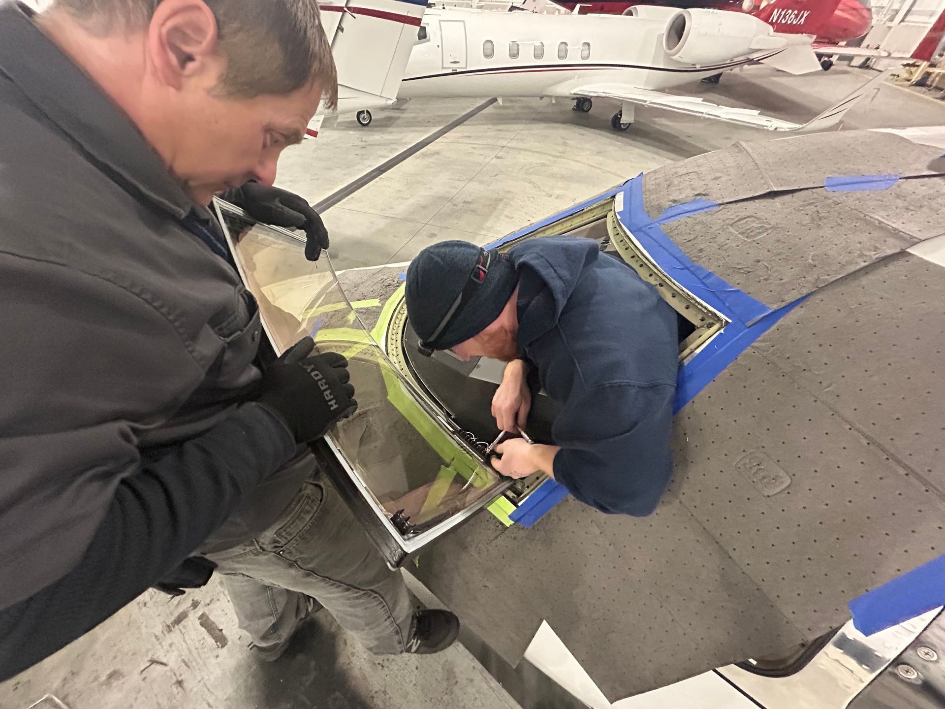 Two men are working on a plane in a hangar.