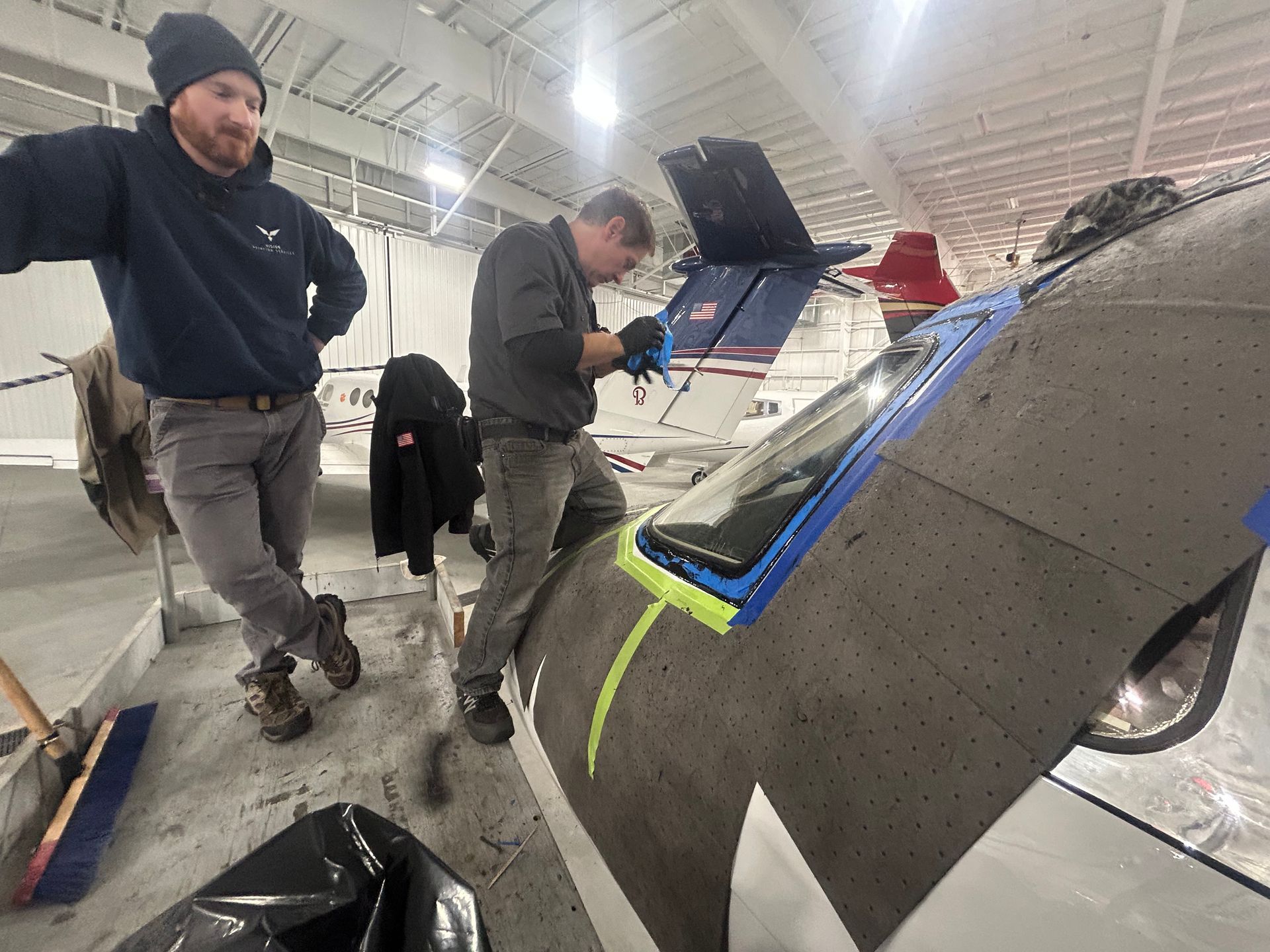 Two men are working on a plane in a hangar.