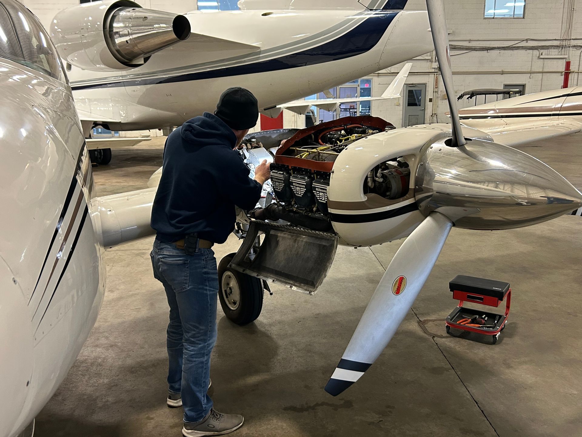 A man is working on an airplane engine in a hangar.