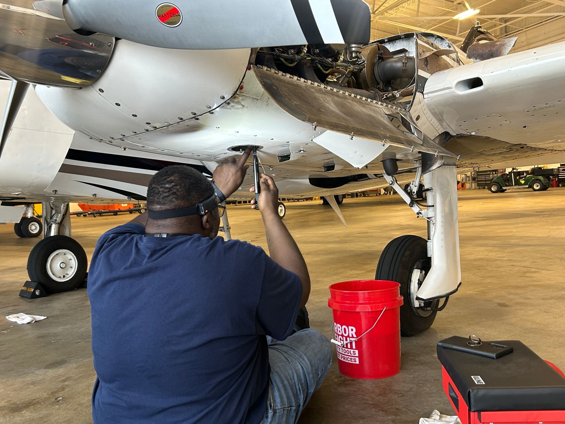 A man is working on an airplane in a hangar.