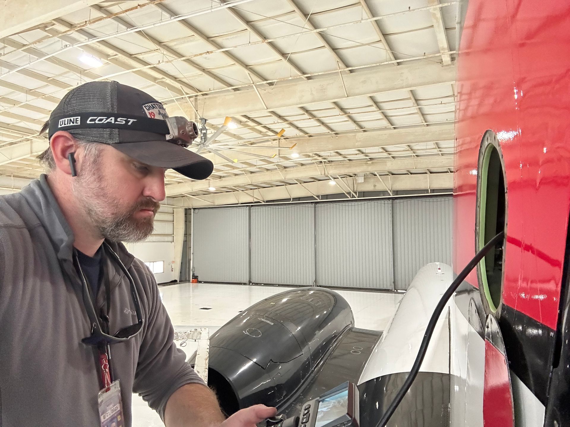 A man is working on an airplane in a hangar.