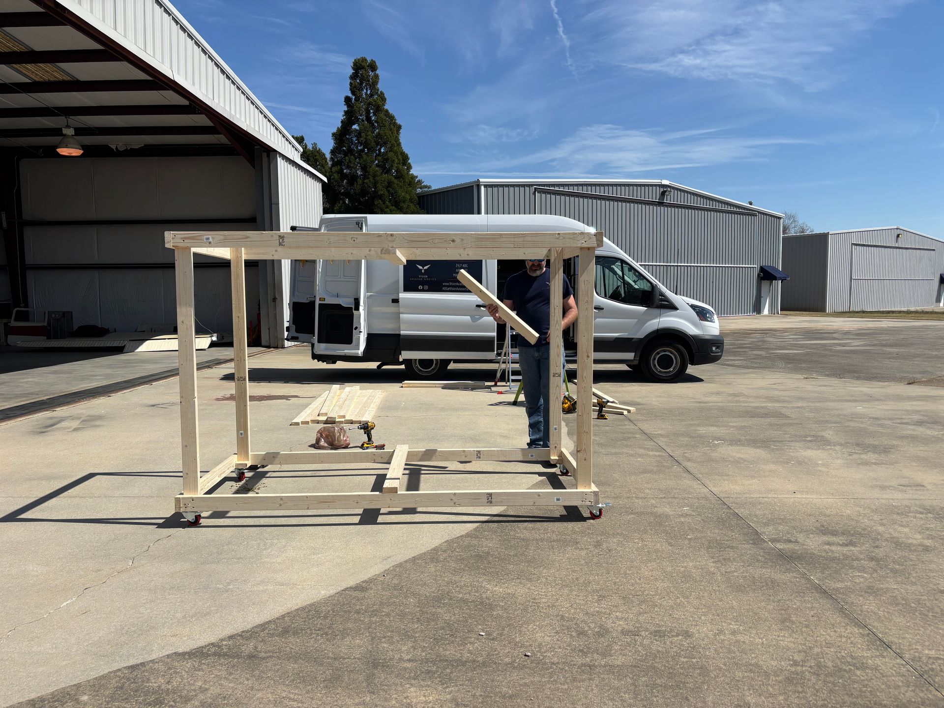 A man is holding a piece of wood in front of a van.