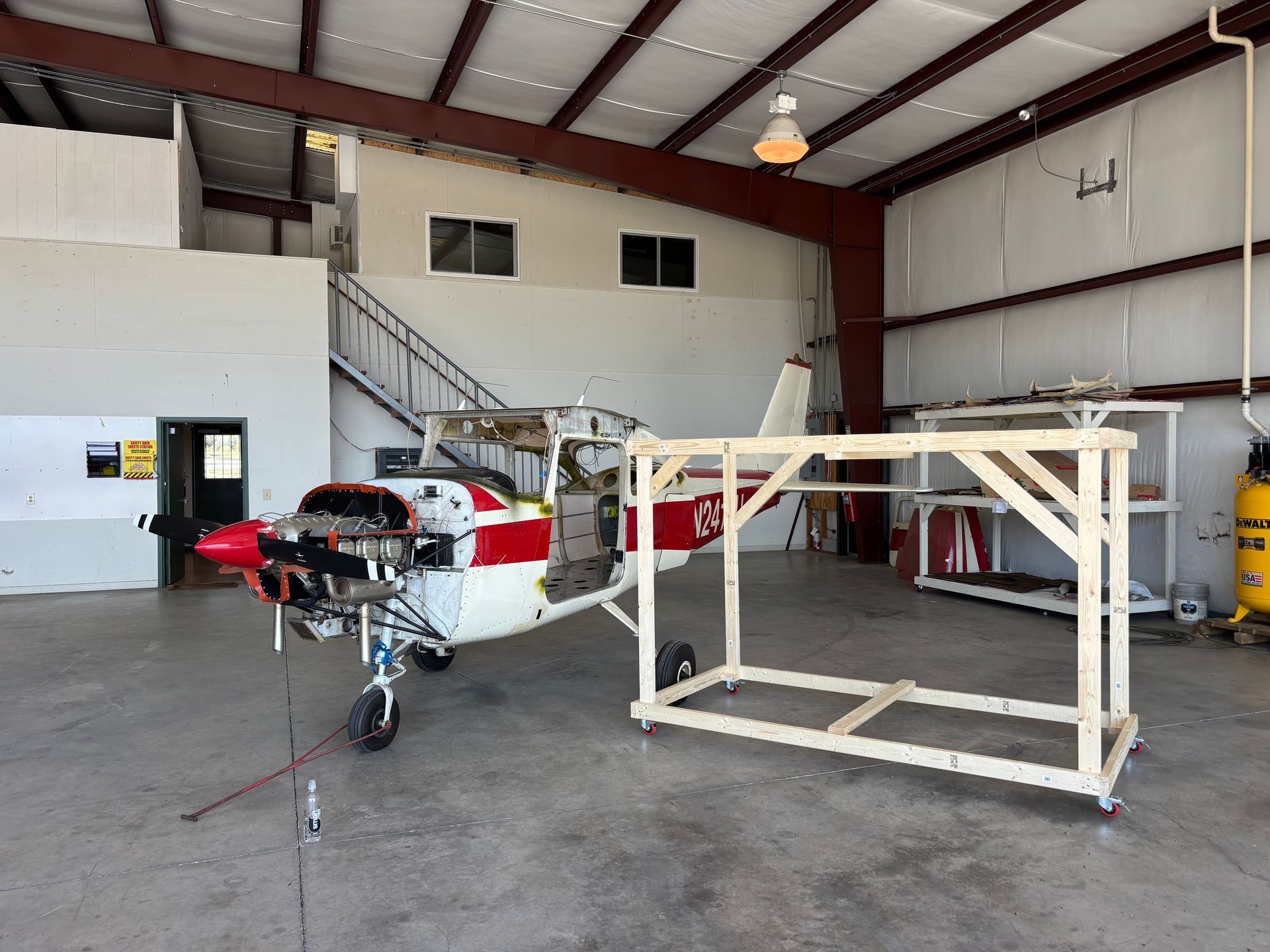 A small red and white plane is parked in a hangar