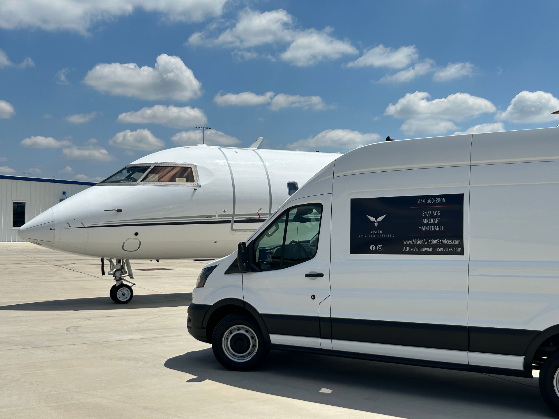 A white van is parked next to a private jet.