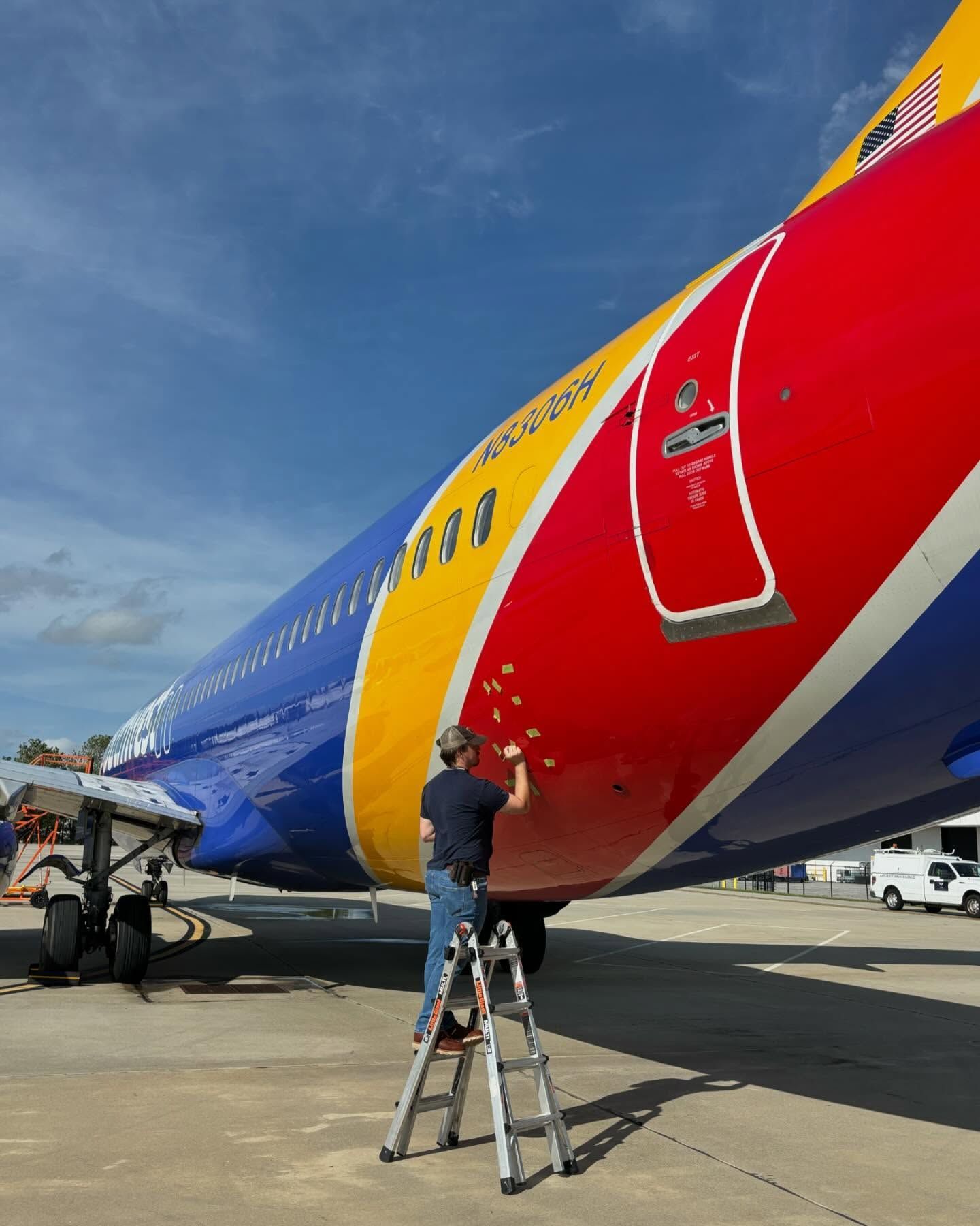 A man on a ladder is working on a southwest airlines plane
