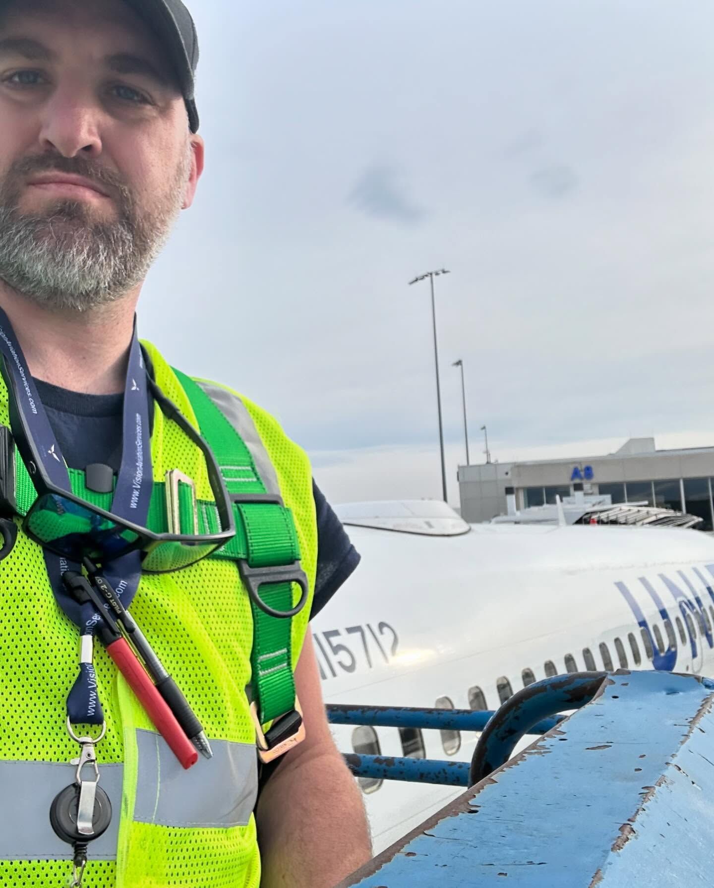 A man in a yellow vest is standing in front of an airplane