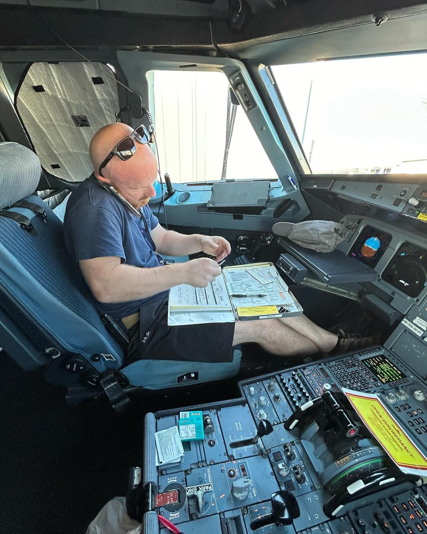 A man wearing sunglasses is sitting in the cockpit of an airplane