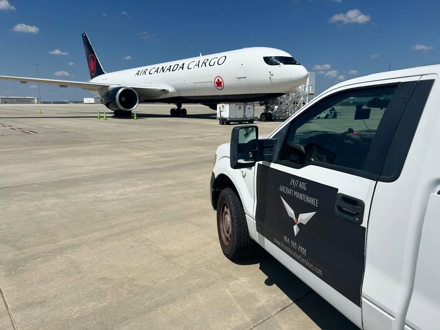 A white truck is parked next to an airplane on the tarmac.