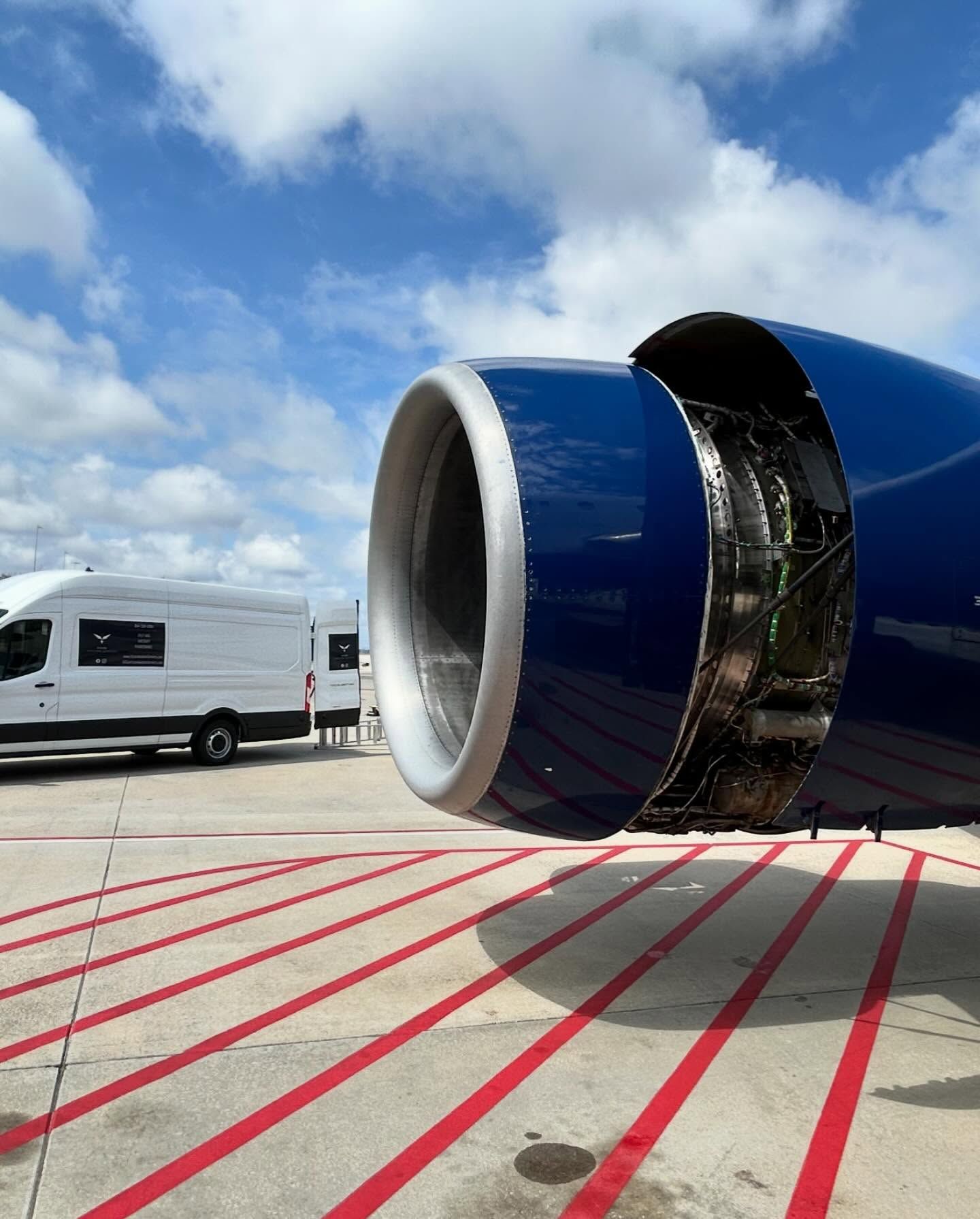 A blue airplane is parked on a runway next to a white van
