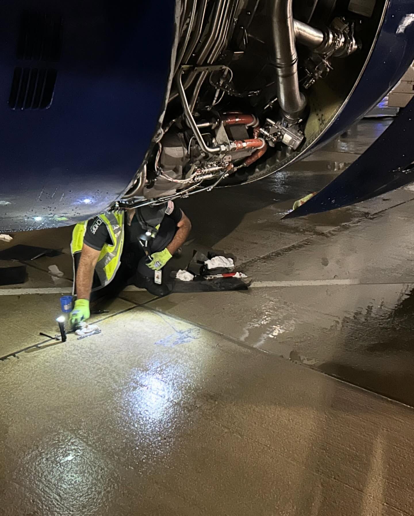 A man is working on the underside of an airplane.