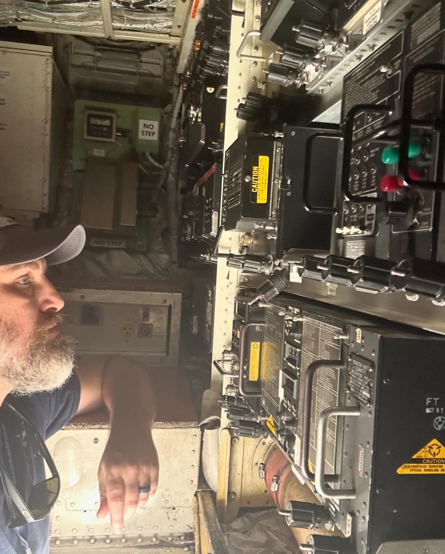 A man in a hat stands in front of a machine that has a yellow sticker on it