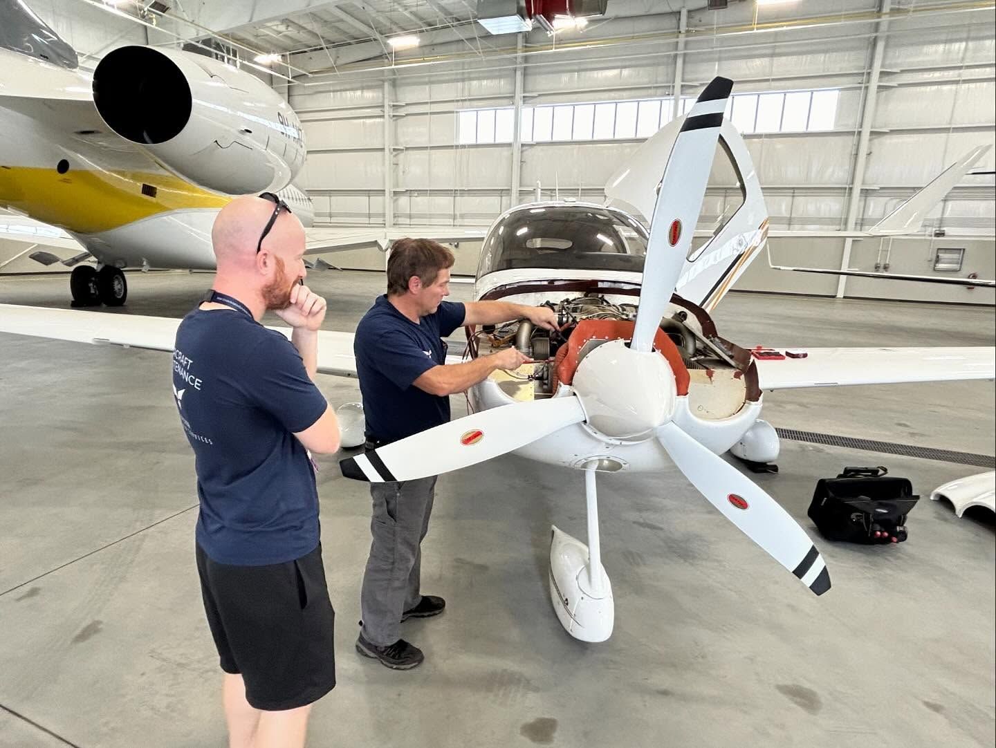 Two men are working on an airplane in a hangar