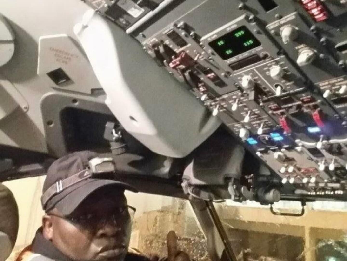 A man in a hat is sitting in the cockpit of an airplane