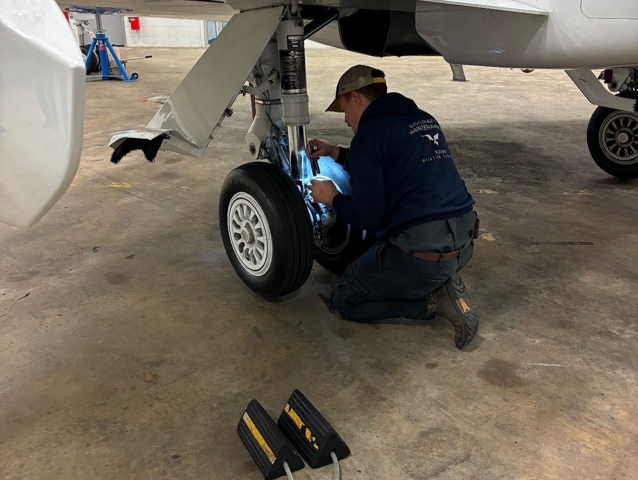 A man is working on a plane in a hangar