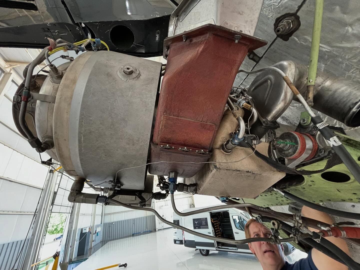 A man is working on an airplane engine in a hangar.