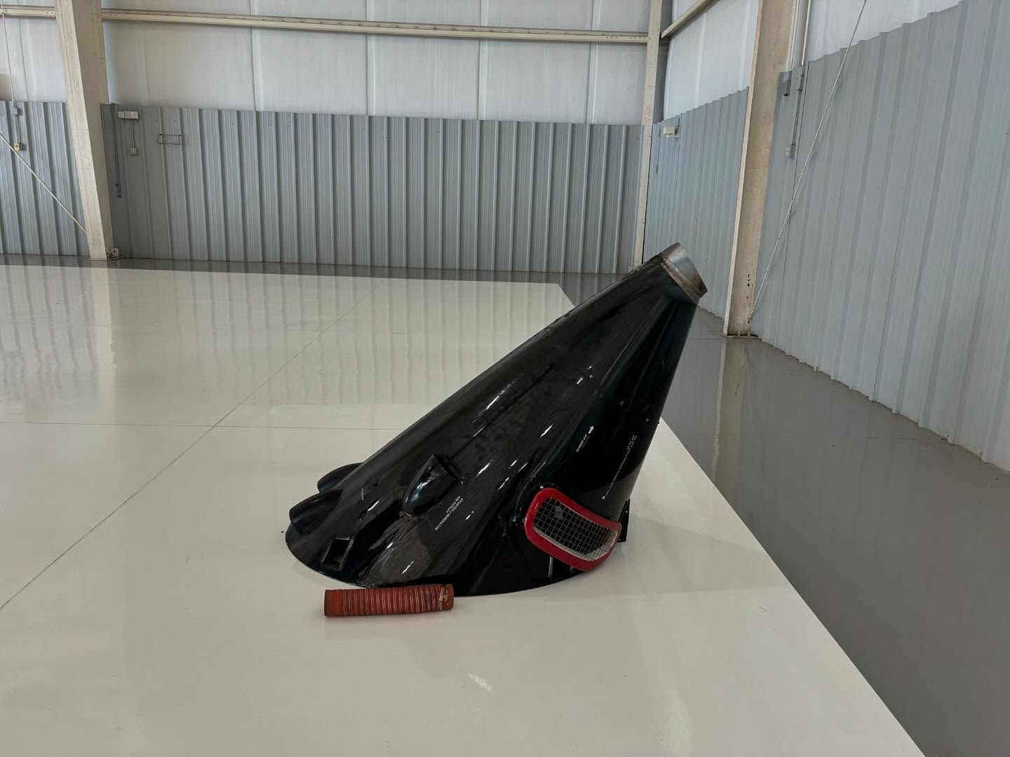 A black object is sitting on a white table in a warehouse.