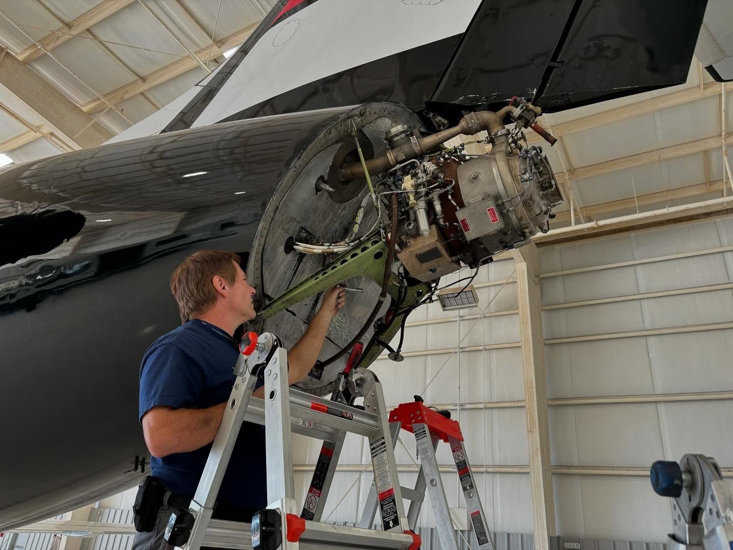 A man is working on an airplane in a hangar